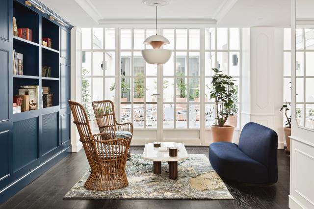 Fauteuils en rotin et canapé bleu outre-mer dans le salon du New Hotel Lafayette à Paris (IXe).