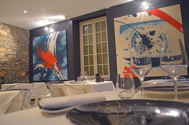 La salle du restaurant gastronomique marie un style moderne, où le gris anthracite, le bleu pétrole et le orange sanguin s'accordent avec de belles pierres apparentes.